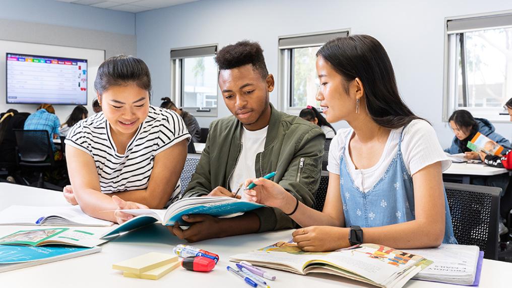 Three students in a group discussion and collaborating with each other, TAFE English Program.