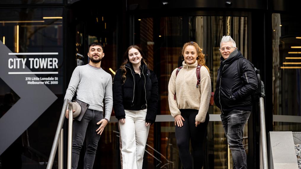 A group of students in front of a glass sliding door denoted: 'city tower'