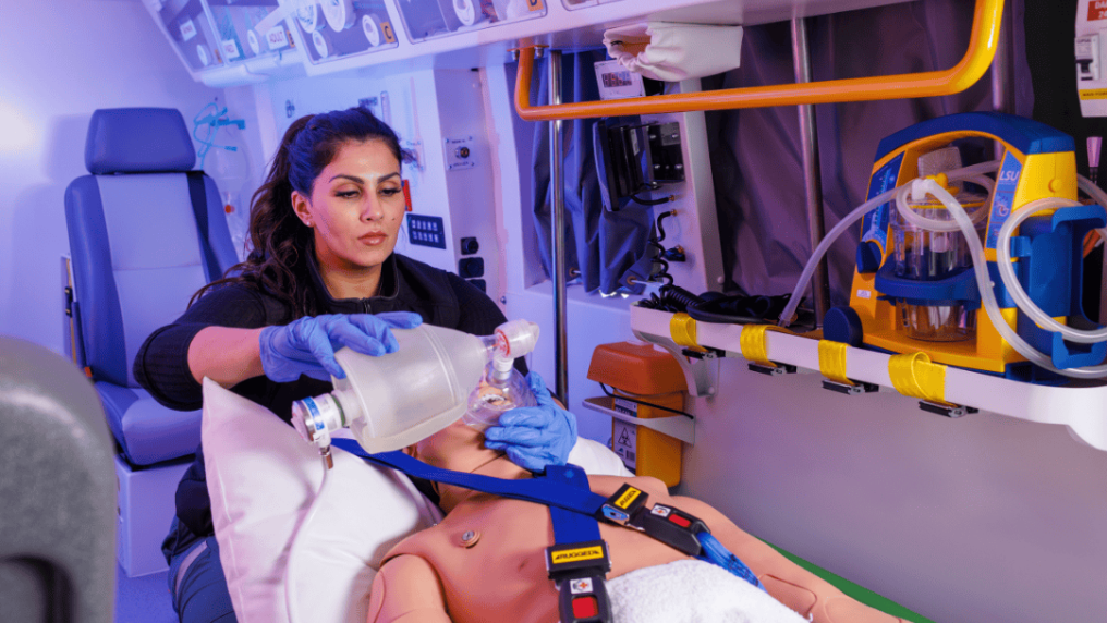 paramedicine student treating a manikin in an ambulance simulation pod