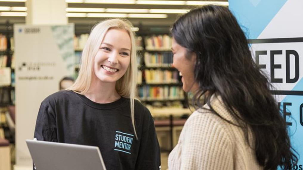 A student mentor smiles welcomingly at a student